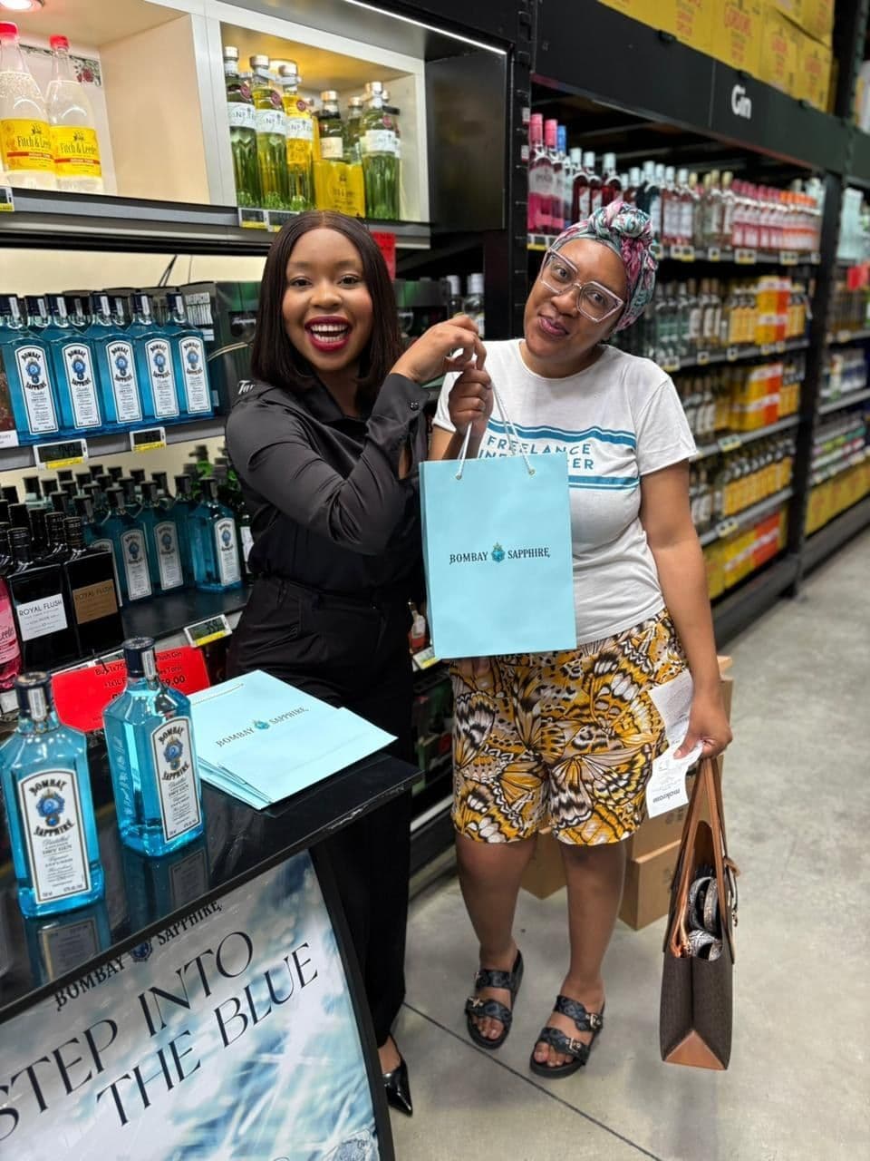A promoter and a shopper sharing a laugh over her gift bag at the Step Into The Blue banner