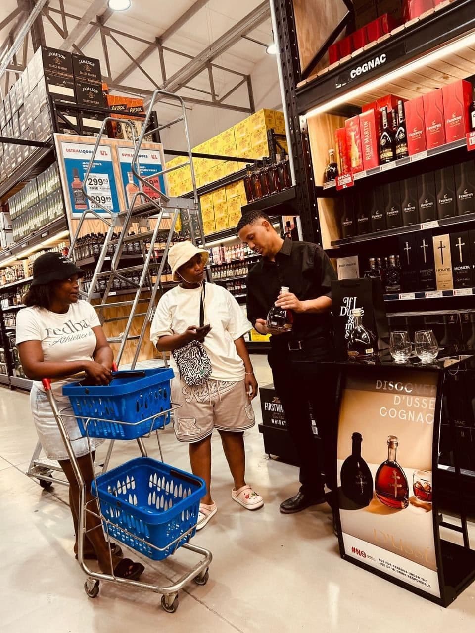 Shoppers with a trolley stacked with blue baskets stopped at the D'Ussé stand, the promoter mid-conversation