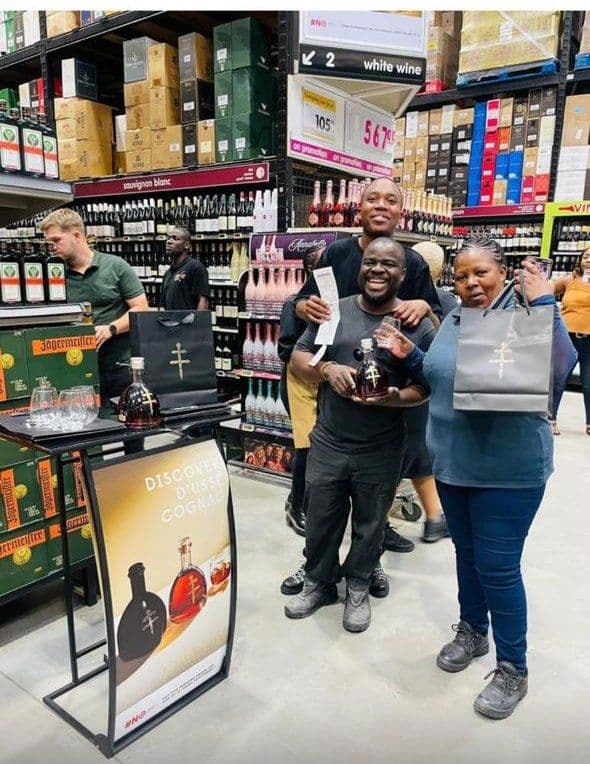 Three shoppers posing with their bottle and gift bags at the D'Ussé stand