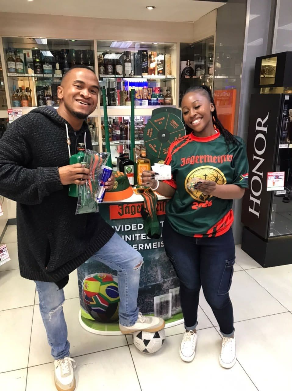A promoter in the campaign jersey handing a shopper his giveaway, a football at their feet