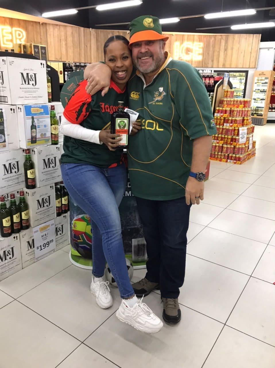 A shopper in a Springbok jersey hugging a promoter in the campaign shirt at the shelf