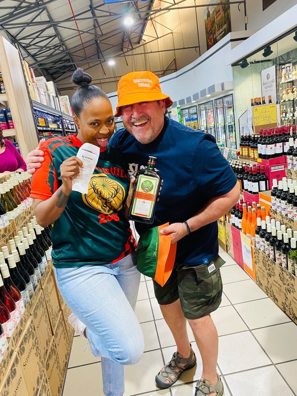 A shopper in an orange bucket hat and a promoter with bottle and flag in the aisle