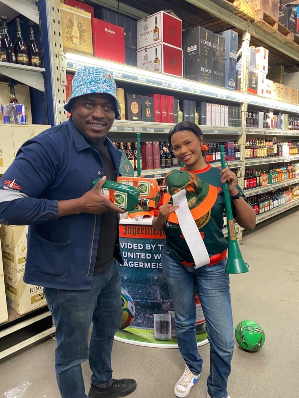 A promoter and a shopper holding the campaign flag between them, a football on the display base