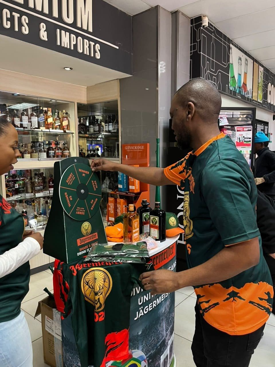A promoter laying the campaign jersey out on the table for a shopper, shot at night