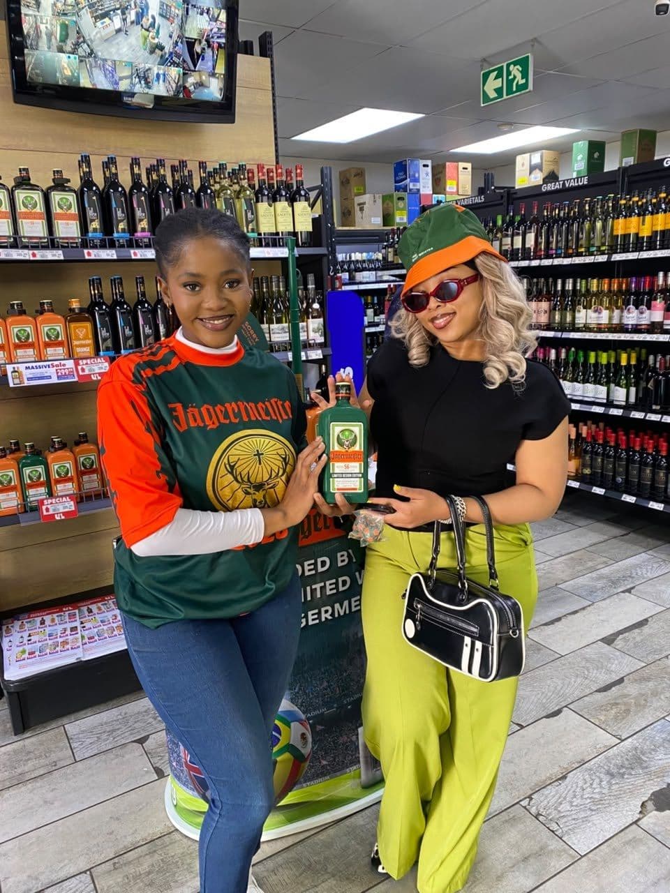 A promoter in the campaign jersey with a shopper in green trousers at the spirits shelf