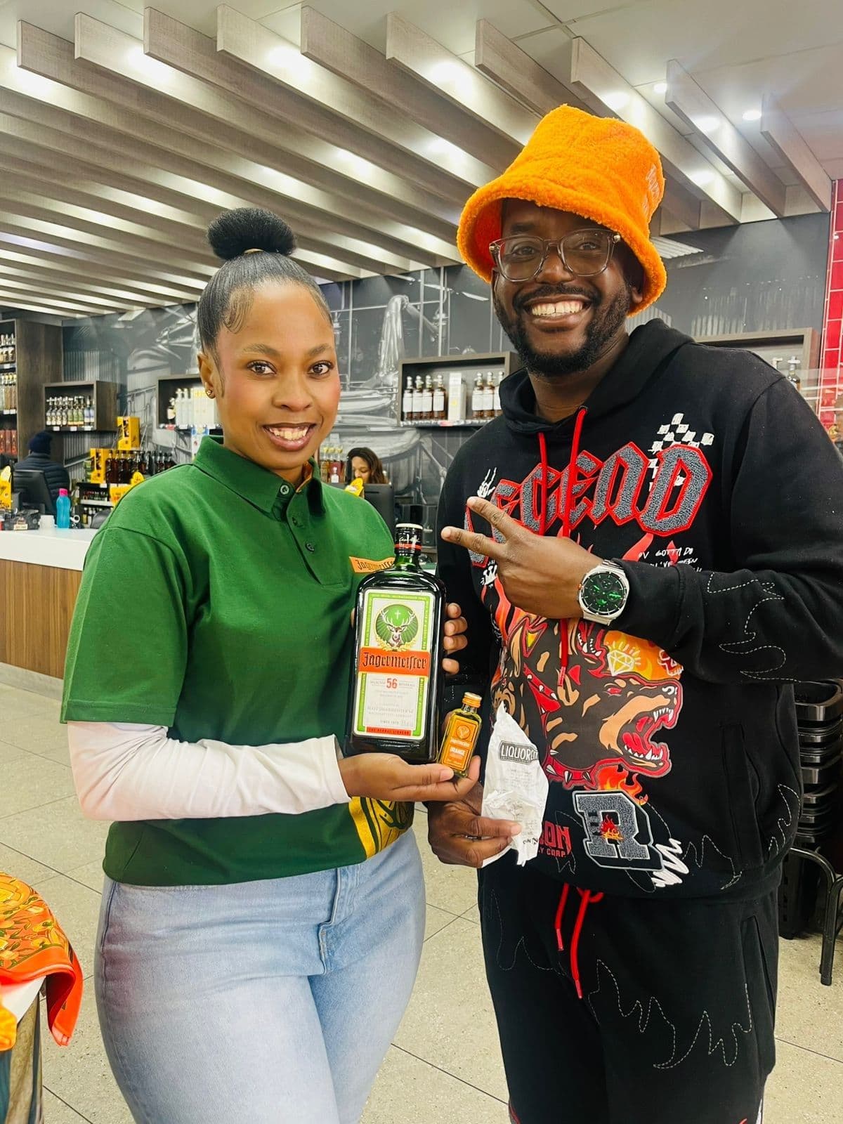 A promoter in the green campaign polo presenting the bottle with a shopper in streetwear
