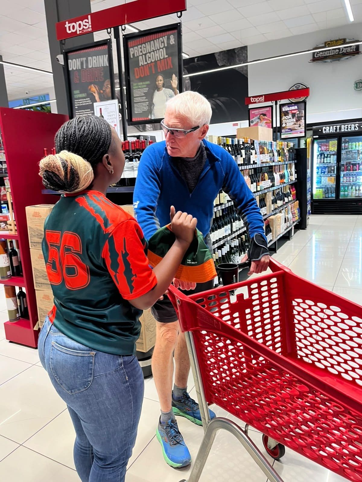 A promoter in the number 56 campaign jersey at the trolleys with a shopper