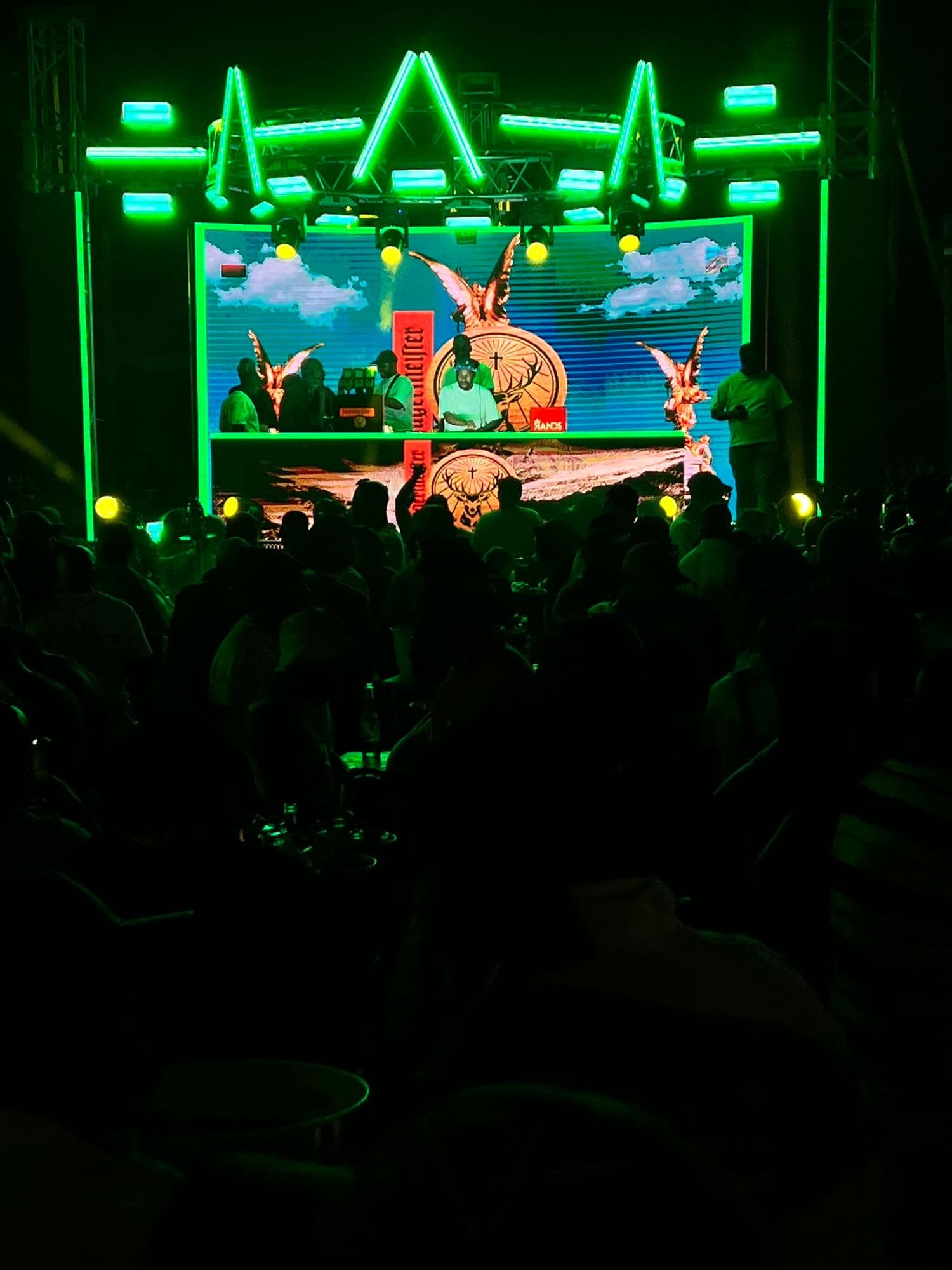 A crowd in front of a Jägermeister main stage traced in green neon, the stag artwork on the screen