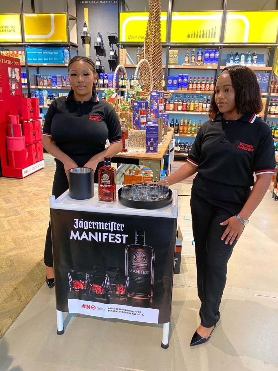 Two promoters standing either side of the branded sampling cart on the store floor