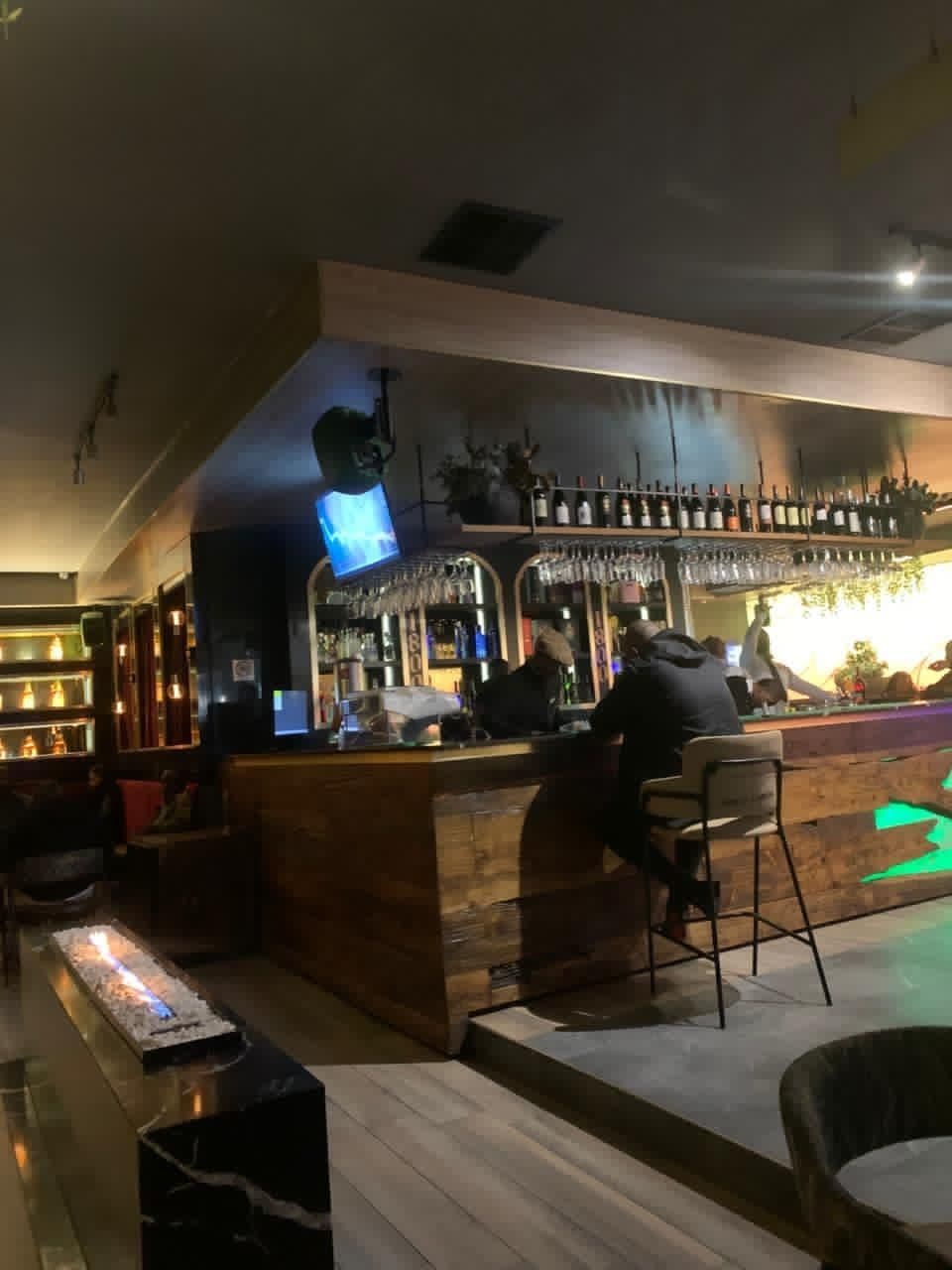 The venue before doors: a long wooden bar under racks of hanging glasses, lit low